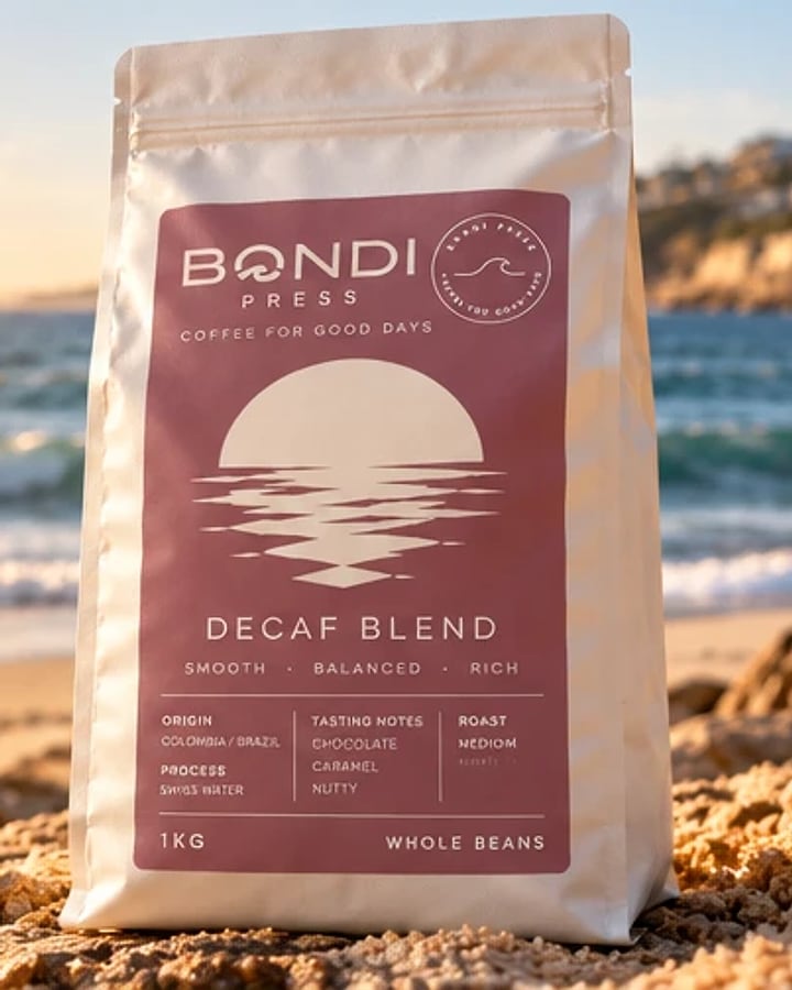 Decaf Blend coffee beans by Bondi Press: white bag with a mauve sunset label on a beach at sunrise